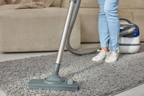 Imagen recortada de una hermosa mujer joven usando una aspiradora mientras limpia la alfombra en la casa — Foto de Stock