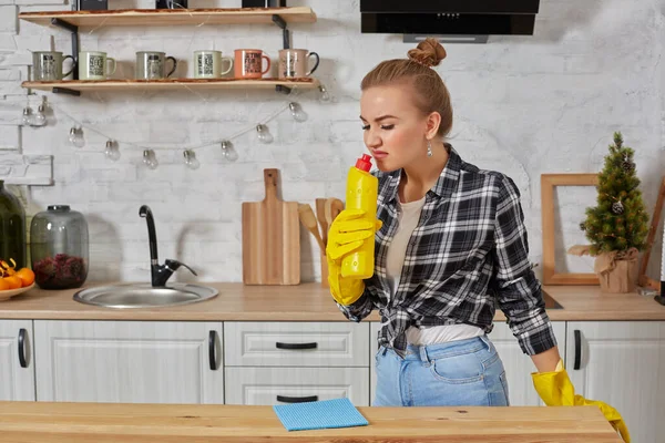 Молодая женщина в резиновых защитных желтых перчатках держит на кухне чистильщиков бутылок. — стоковое фото
