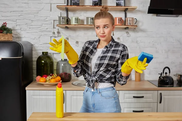 Молодая женщина или домохозяйка в резиновых перчатках вытирает стол микроволоконной тканью на домашней кухне. — стоковое фото