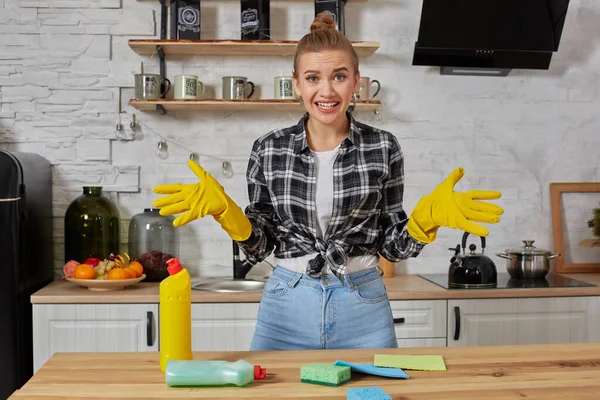 Young woman wearing apron sitting with heap of cleaning sponges indoors — Stock Photo, Image