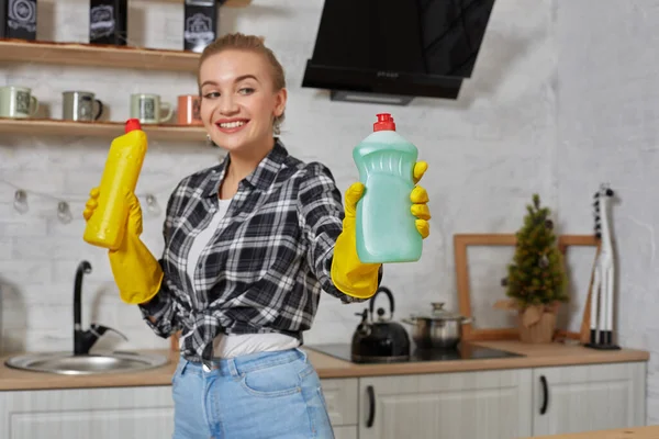 Donna che confronta i prodotti detergenti, tiene due bottiglie e le controlla in cucina. — Foto Stock