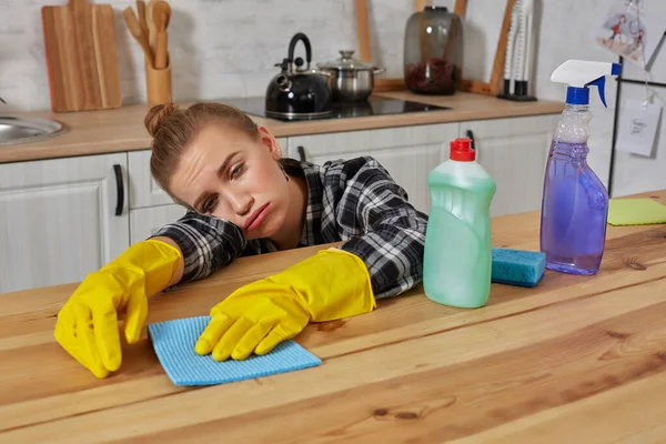 Jovem mulher em luvas de proteção limpa uma mesa na cozinha com um pano — Fotografia de Stock