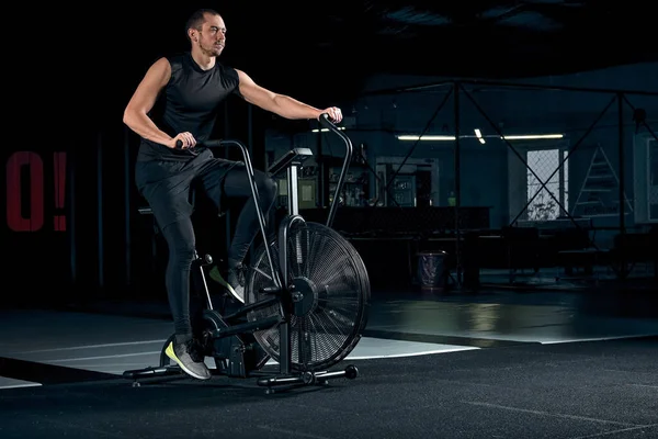 Mężczyzna korzystający z roweru pneumatycznego do treningu wytrzymałościowego na siłowni. — Zdjęcie stockowe