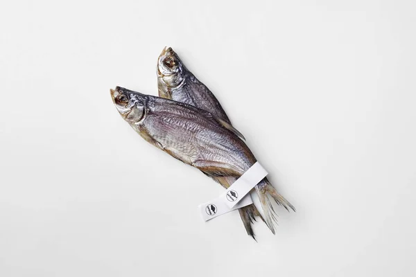 Deux poissons gardons salés séchés avec des étiquettes en papier sur les queues isolées sur blanc — Photo