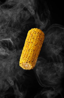 Siyah arka planda buharda uçuşan mısırın ızgara kulağı