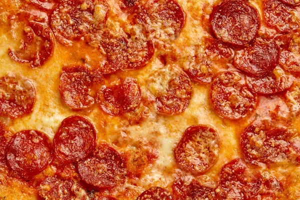 Closeup de fatias de pepperoni cobertas com mussarela derretida em pizza assada — Fotografia de Stock