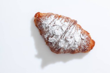 Badem gevreği ve beyaz üzerine pudra şekeri serpiştirilmiş kruvasan.