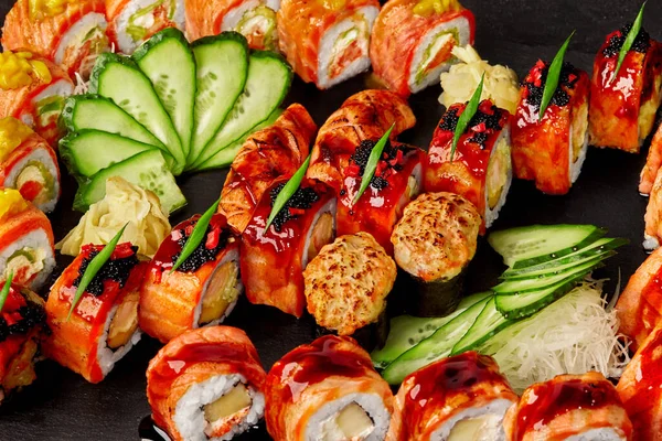 Zbliżenie zestaw rolki, nigiri sushi i gunkan maki z łososia na czarnym tle — Zdjęcie stockowe