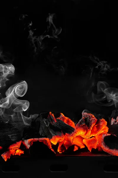 Hot smouldering charcoals on bbq grill on black background with white smoke — Stock Photo, Image