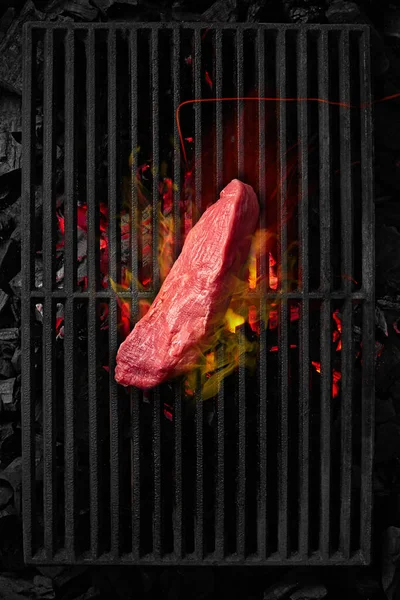 Morceau de filet de veau cuit sur une grille grillade noire au-dessus de charbons en feu — Photo