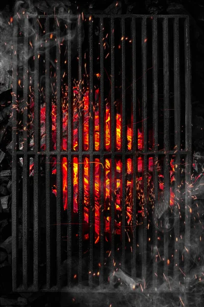 Vista superior a través de la parrilla de barbacoa negra de carbones en llamas con chispas y humo blanco — Foto de Stock