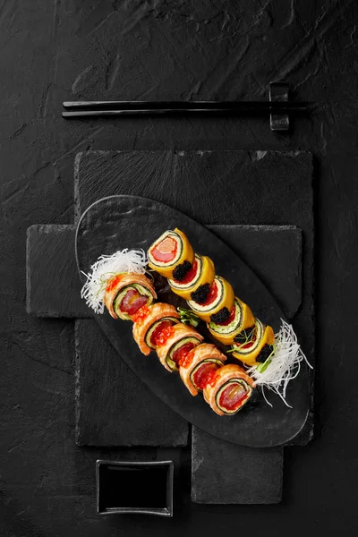 Uramaki roll with salmon, tuna, mango and avocado topped with tobiko and red caviar on slate board — Stock Photo, Image