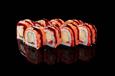 Philadelphia ekmekleri kızarmış somon, krem peynir, tobiko ve siyah arka planda elma.