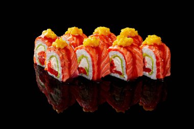 Krem peynirli Uramaki dürümü, tobiko, avokado, kurutulmuş somon, siyah arka planda mango.