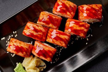 Kurutulmuş somon suşisi unagi soslu ve susamlı, turşulu zencefil ve wasabi ile servis ediliyor.