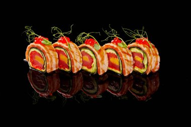 Ton balığı, mango, tobiko, avokado, kurutulmuş somon ve siyah arka planda kırmızı havyar ile Uramaki rulosu.