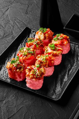 Kızarmış karides, dolma biber, soya soslu soğan ve siyah tabakta mamenori.