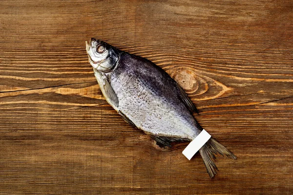 Top view of salted jerked roach fish with label on tail on wooden background