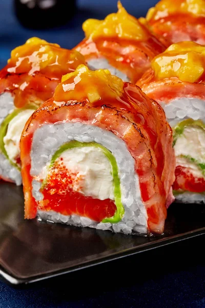 Zbliżenie sushi roll z serem śmietankowym, tobiko, awokado, palony łosoś, mango — Zdjęcie stockowe