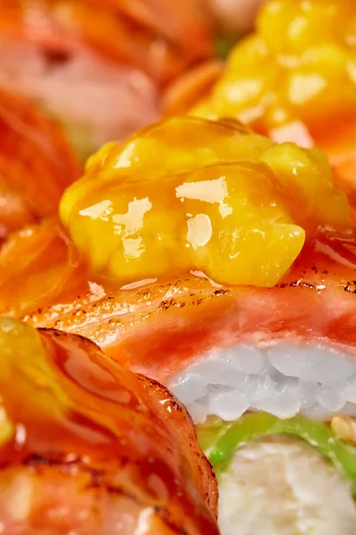 Macro shot de peças de manga caramelizadas em fatias de salmão em rolo de sushi — Fotografia de Stock