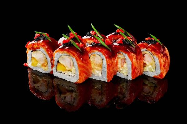 Łososiowe bułki sushi z krewetkami, serem śmietankowym i mango zwieńczone sosem teriyaki, kawior na czarnym tle — Zdjęcie stockowe