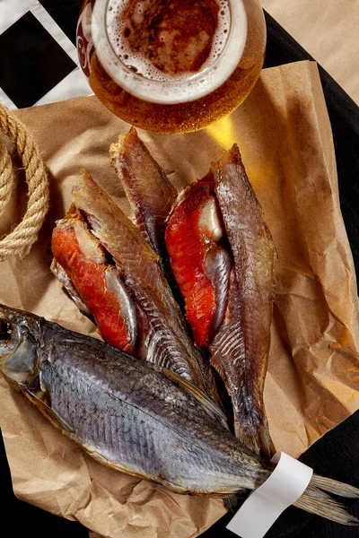 Whole and skinned salted air-dried roach with roe served on wrapping kraft paper with beer