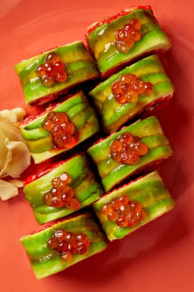 Avokadoya sarılı kırmızı havyarlı uramaki dürümünün üst görüntüsü