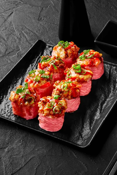 Kızarmış karides, dolma biber, soya soslu soğan ve siyah tabakta mamenori.