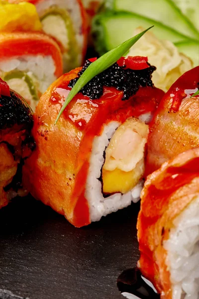 Uramaki roll with shrimp, mango, salmon, black tobiko and unagi sauce with assorted sushi — Stockfoto
