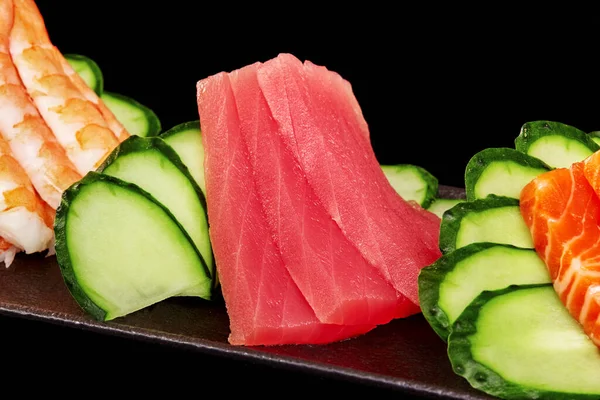 Detailní záběr syrového tuňáka sashimi na talíři s lososem, krevetami a okurkou — Stock fotografie