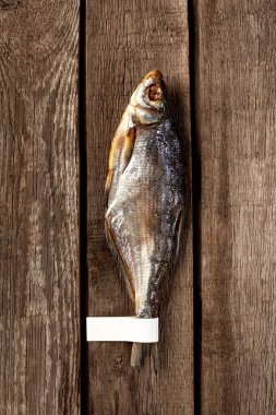 Kaba ahşap zeminde kuyruğu olan güneşte kurutulmuş hamamböceği balığı.