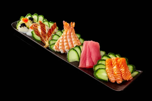 Sashimi set with raw salmon, tuna, grilled unagi eel, cuttlefish and tobiko on black background — Stock Photo, Image