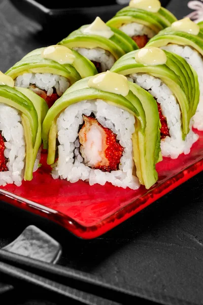 Closeup of uramaki rolls with shrimp, tobiko, avocado and mayonnaise on red plate — Stockfoto