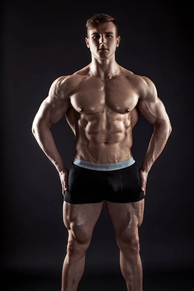Muskulös bodybuilder killen gör poserar över svart bakgrund — Stockfoto