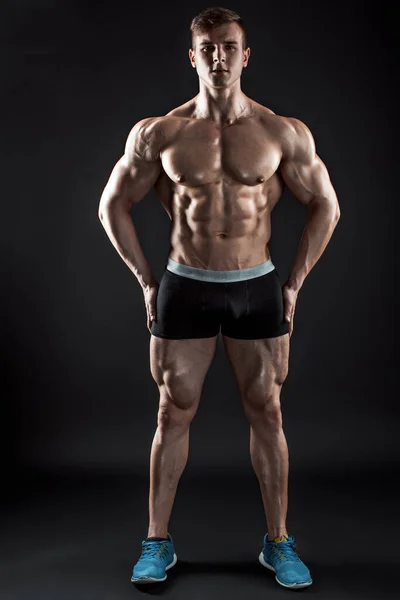 Muskulös bodybuilder killen gör poserar över svart bakgrund — Stockfoto