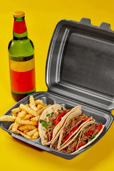 Birria tacos in takeaway container with fries and bottle of drink on yellow background — Fotografia de Stock