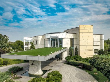 Private mansion in suburbs with geometric shapes, wide windows and porch roof with green artificial grass