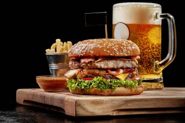 Hamburger with two patties, bacon, cheese, caramelized onions, tomatoes served with light beer, fries and aioli
