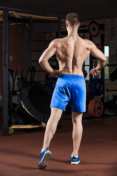 Человек, стоящий крепко в спортзале и сгибающий мышцы — стоковое фото