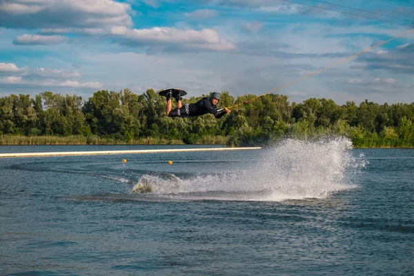 Man öva tricks på wakeboard, hoppa över vatten hålla på bogserlina — Stockfoto