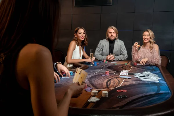 Soustředěný muž a dvě usměvavé dámy hrající poker u herního stolu v kasinu — Stock fotografie