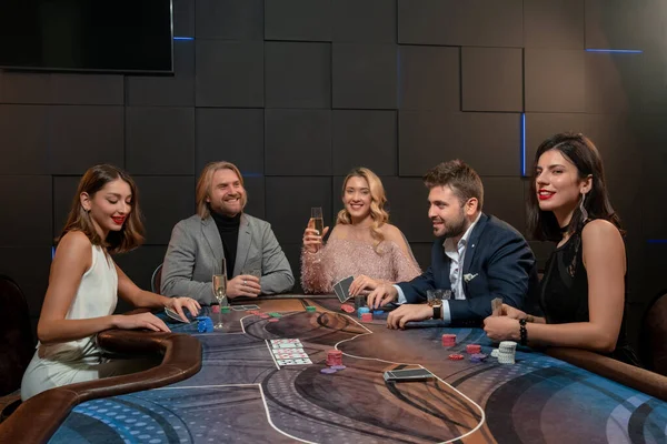 Přátelští lidé pití alkoholu a hraní pokeru u herního stolu v kasinu — Stock fotografie