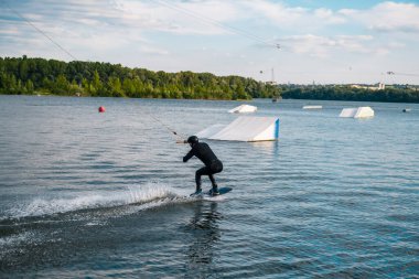 Wakeboardcu suda kayıyor rampa atlayışı yapmaya hazırlanıyor.