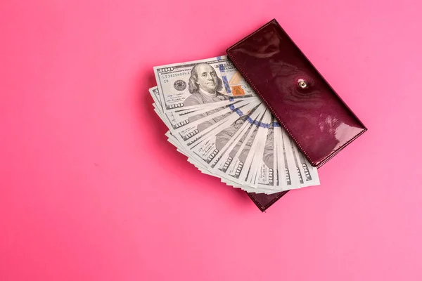 Dużo banknotów w czerwonej damskiej torebce na różowym tle. — Zdjęcie stockowe