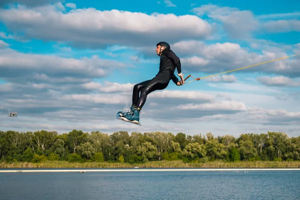 Člověk cvičit techniku skákání přes vodu s rotací během wakeboarding školení — Stock fotografie