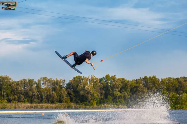 Young man skilfully making tricks on wakeboard on sunny day — Stock Photo, Image