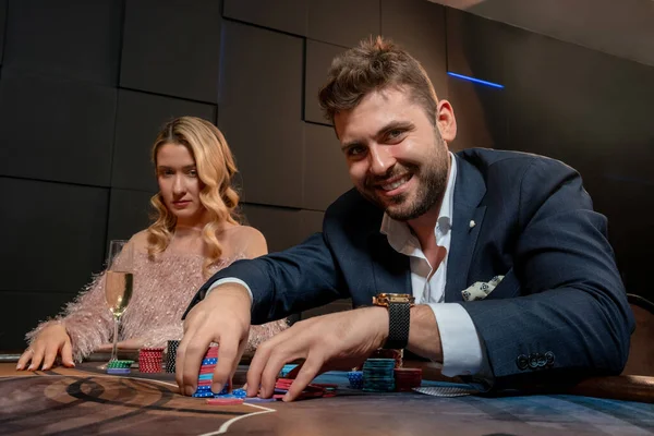Tipo barbudo emocionado sosteniendo fichas de apuestas en la mesa de póquer en el casino — Foto de Stock