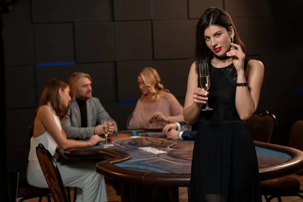 Mladá brunetka zvyšování sklenice šampaňského k úspěšné pokerové hře v kasinu — Stock fotografie