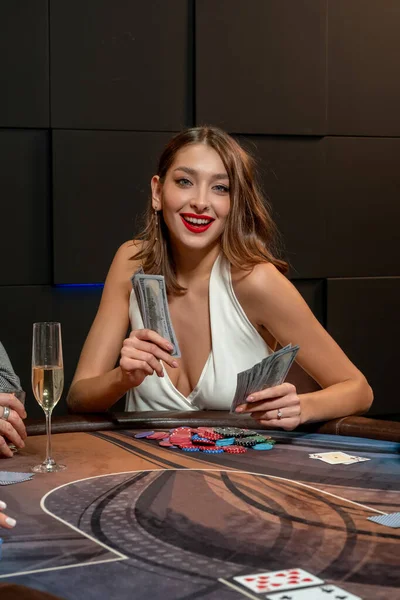 Šťastná dívka sedí u pokerového stolu v kasinu s fanouškem bankovek — Stock fotografie