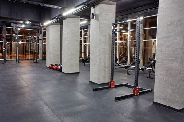 Varias máquinas de ejercicio para entrenamiento físico y sección para crossfit en el interior espacioso y vacío del gimnasio con enormes ventanas. Deporte, fitness —  Fotos de Stock